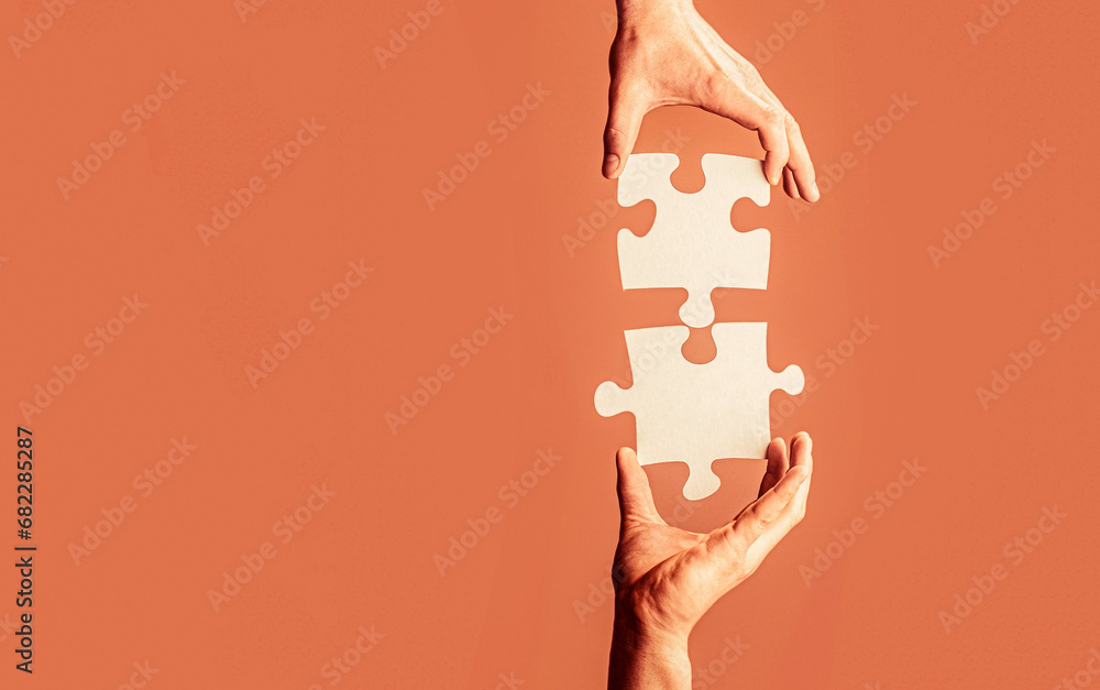 Closeup hands of man connecting jigsaw puzzle. Two hands trying to connect couple puzzle. Hand connecting jigsaw puzzle. Man hands connecting couple puzzle piece - obrazy, fototapety, plakaty 