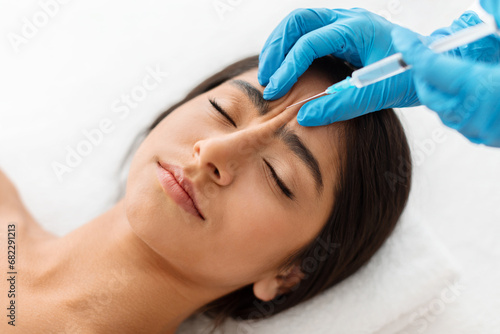 Indian woman getting cosmetic injection between eyebrows at beauty center