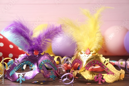 Beautiful carnival masks and party decor on wooden table, closeup