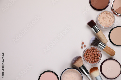 Different face powders and makeup brushes on light background, flat lay. Space for text