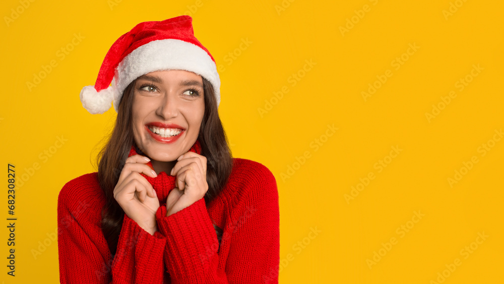 woman posing with Santa hat cheerfully looking aside, yellow backdrop woman posing with Santa hat cheerfully looking aside, yellow backdrop