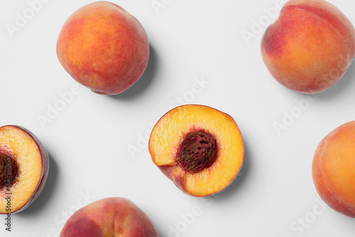Cut and whole fresh ripe peaches on white background, flat lay