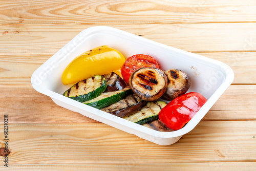Grilled vegetables. Healthy diet. Takeaway food. Eco packaging. On a wooden background.