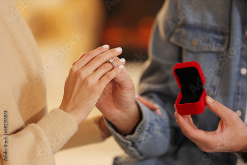 Making proposal. Man putting engagement ring on his girlfriend s finger against blurred background  closeup