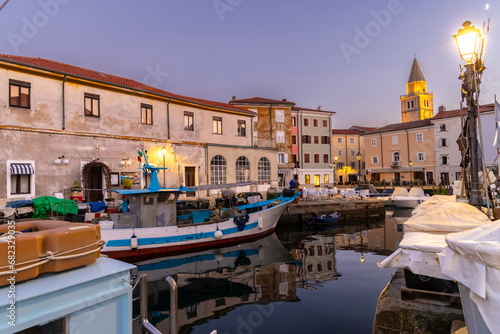 Evening atmosphere in the old harbour of Muggia, a coastal town near Trieste in northern Italy with moored small motor boats.