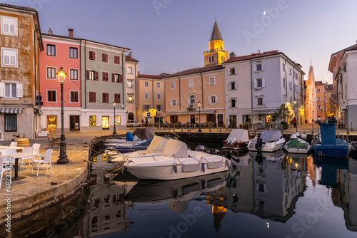 Evening atmosphere in the old harbour of Muggia, a coastal town near Trieste in northern Italy with moored small motor boats.