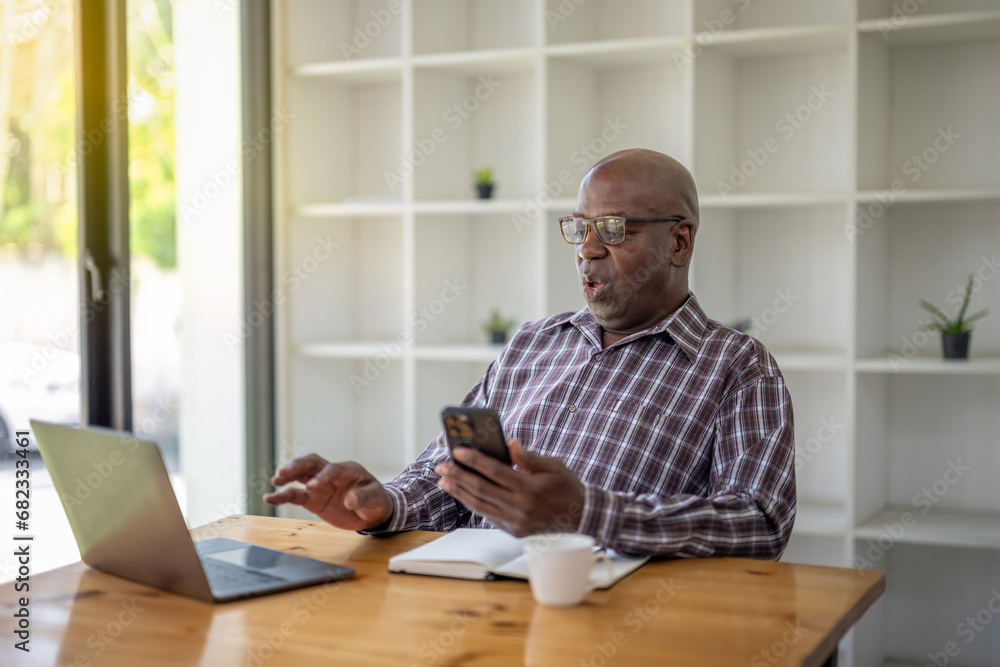 Senior black man talking on the phone and using at the laptop, video call recommend and consult. Senior black man talking on the phone and using at the laptop, video call recommend and consult.