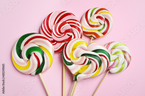Sticks with different colorful lollipops on pink background, flat lay