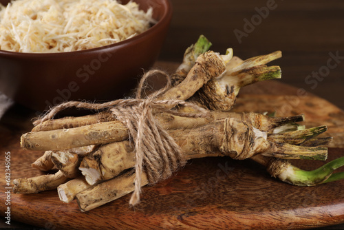 Fresh raw horseradish roots on wooden board, closeup
