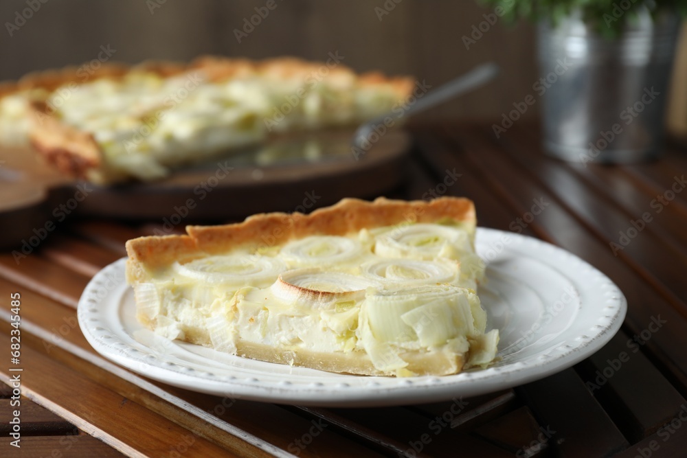 Plate with piece of tasty leek pie on wooden table, closeup Plate with piece of tasty leek pie on wooden table, closeup