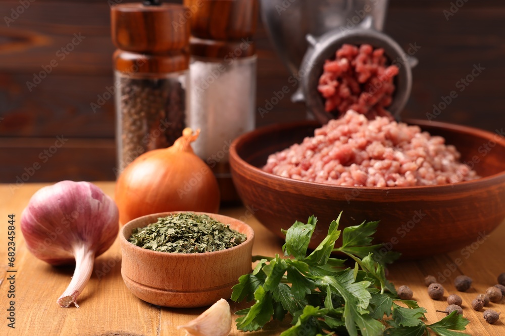 Manual meat grinder with beef mince, spices and parsley on wooden table, selective focus Manual meat grinder with beef mince, spices and parsley on wooden table, selective focus