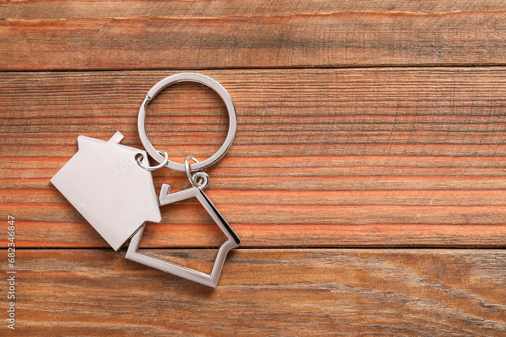 Metal keychain in shape of houses on wooden table, top view. Space for text Metal keychain in shape of houses on wooden table, top view. Space for text