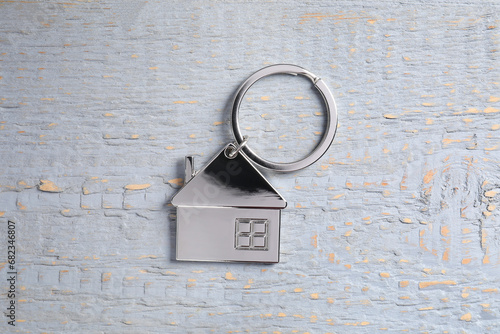 Metal keychain in shape of house on grey wooden table, top view © New Africa