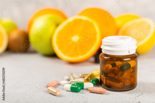 Vitamins and supplements. Variety of vitamin tablets in a jar on a texture background.Multivitamins with fresh and healthy fruits.Food supplements. Flat lay. Space for text.Copy space