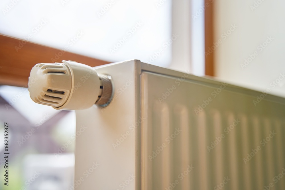 Radiator in the apartment. White heated battery. Thermostat head of a heating radiator in an apartment, office. Radiator in the apartment. White heated battery. Thermostat head of a heating radiator in an apartment, office.