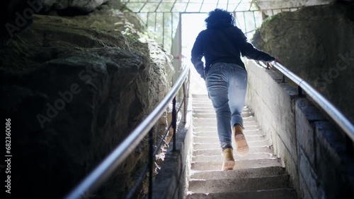 Woman climb on stairs visiting mystic view underground cave Devil's Throat (Dyavolsko garlo ) cave in the Rhodope Mountains photo