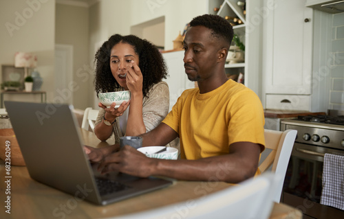 Young multiethnic couple working on a laptop during breakfast at home © mavoimages