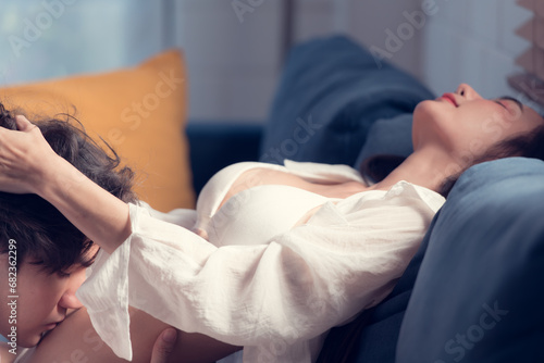 In the living room at home, a sexy woman in lingerie lies on the sofa in love with her spouse.