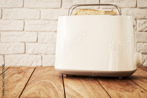 White electric toaster with toasted bread sticking out of it. Home cooking and kitchen theme