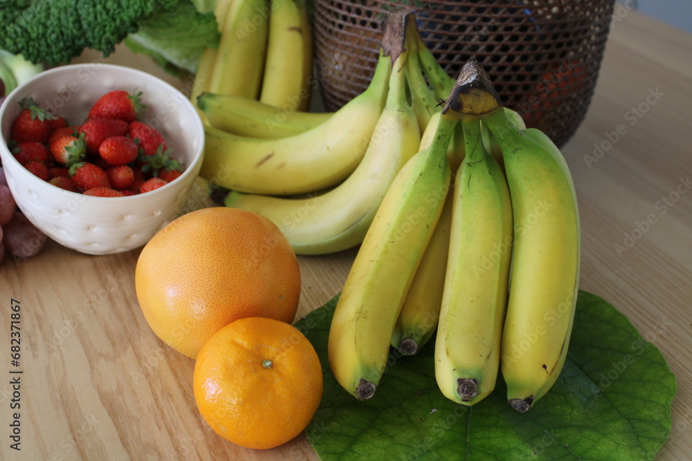 Régime de banane, bananes et fruits frais sur la table de la cuisine