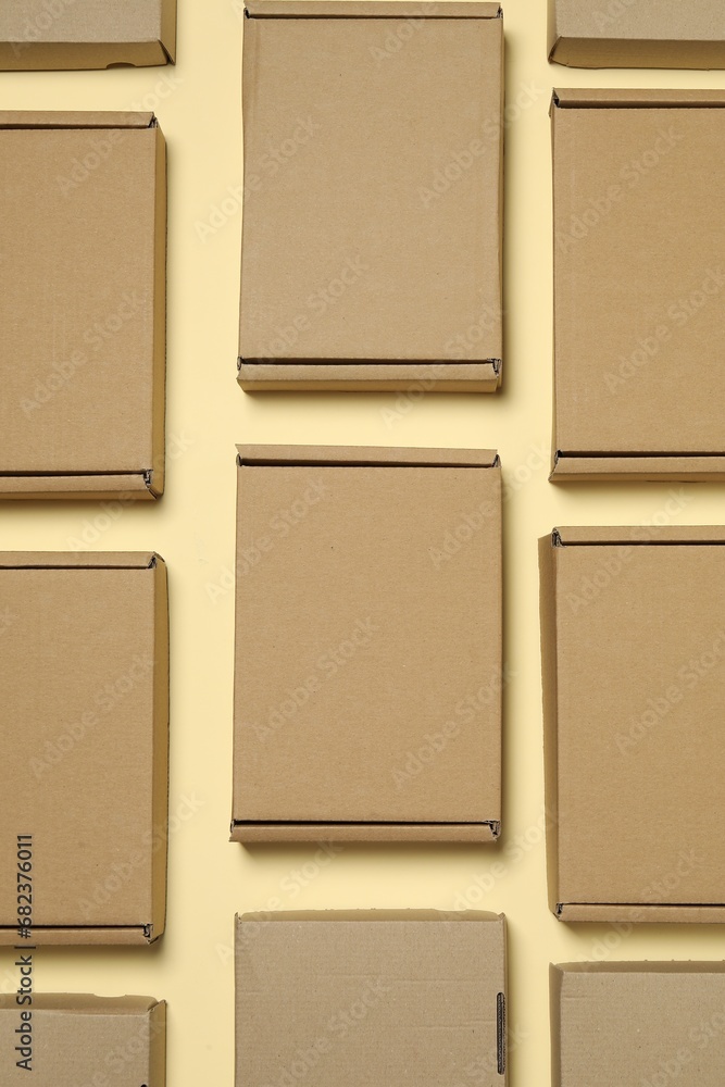 Fototapeta premium Many closed cardboard boxes on pale yellow background, flat lay