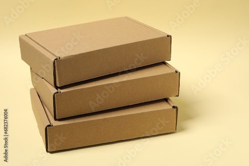 Stack of closed cardboard boxes on pale yellow background
