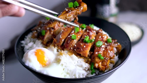 Chopsticks with Delicious sweet chopping chicken rice,  teriyaki, sesame seeds, sliced spring onions, broccoli, and vegetables. Asian food, Japanese food	