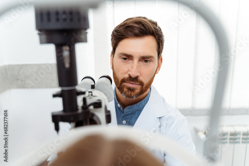 Male optometrist checking eyesight for little girl in optics