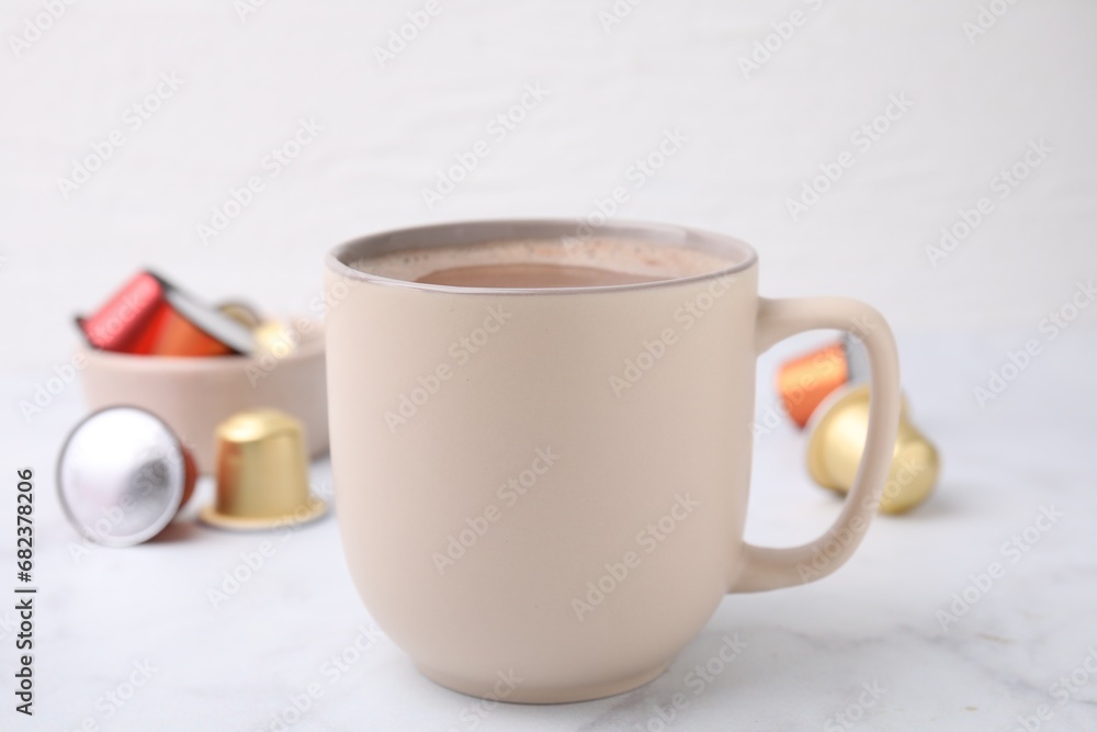Cup of coffee and capsules on white marble table, closeup Cup of coffee and capsules on white marble table, closeup