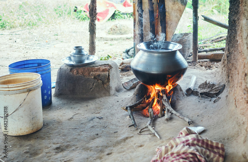 rice being cooked in aluminium utensil with logs burning under mud chulha (clay stove). At a tribal village in Bandwan, Purulia, where most people belong to economically backward class. photo