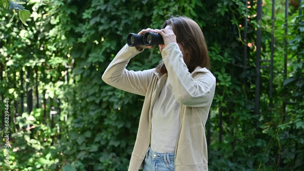 Young woman playing with binoculars, joyfully looking into the distance Young woman playing with binoculars, joyfully looking into the distance