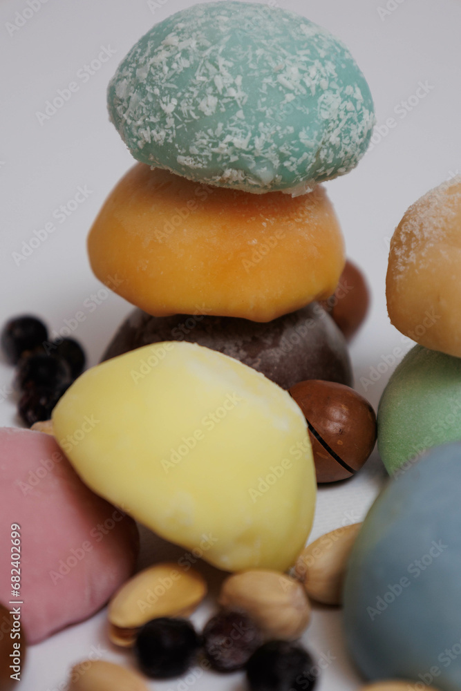 Japanese rice desert mochi closeup. Colouful mochi cakes sliced. Tasty fruit and chocolate mochi on grey background. Traditional cold ice asian candy. Dry fruits and nuts. Japanese rice desert mochi closeup. Colouful mochi cakes sliced. Tasty fruit and chocolate mochi on grey background. Traditional cold ice asian candy. Dry fruits and nuts.
