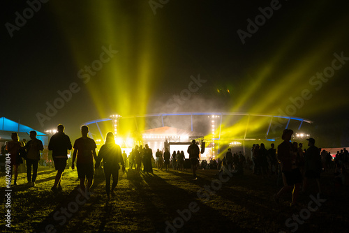 People attending a music festival. Walking down the brightly decorated avenue to reach the concert hall with flashing lights