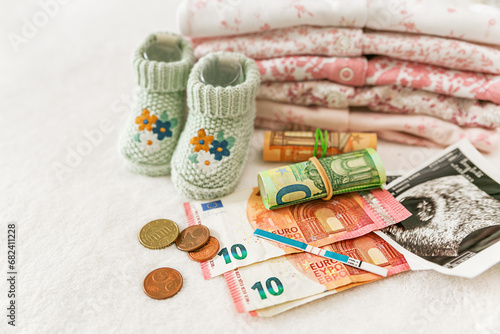 Pregnancy planning. Pregnancy test, money, ultrasound photo of a child and baby clothes on a white background, price for IVF, money for a child, government payments for a child, medical insurance