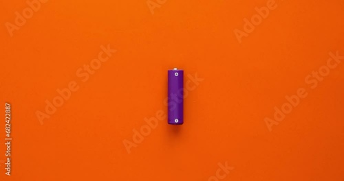 Battery and lightning bolts flying from it on an orange background. 4K stop motion animation photo