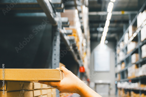 Cardboard box package with hand of Asian shopper woman picking product from shelf in warehouse. customer shopping lifestyle in department store or purchasing factory good concepts.