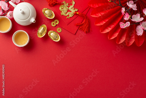 Lunar New Year Reunion Tradition. Top view table adorned with traditional Chinese New Year elements—red envelopes, decorative items, teapot set with cups on festive red backdrop, space for text or ads