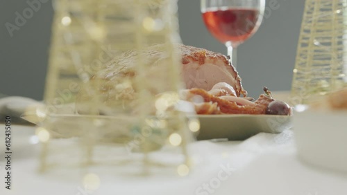Christmas Dinner or Lunch with Glazed Holiday Ham sliced on wooden table. Vegetables, Wine and gammon or ham on beautiful table. Festive season and holiday time. The perfect family meal. Zoom out.