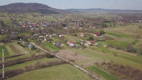 Cieklin, Poland - 4 9 2019: Panorama of a small European village with a Christian Catholic church in the center. Farms among green picturesque hills. Panorama of the Carpathian region with a drone