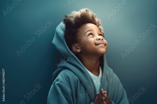 Little black boy on knees holding hands and praying in the morning, pastel neutral background. Christianity, faith, spirituality, religion, salvation, peace, faith concept. Kid praying to God