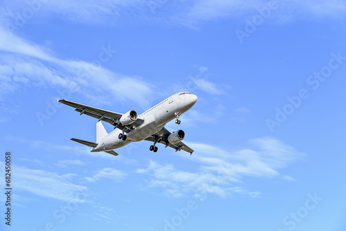 Passenger plane landing at the airport, under a blue sky with white clouds