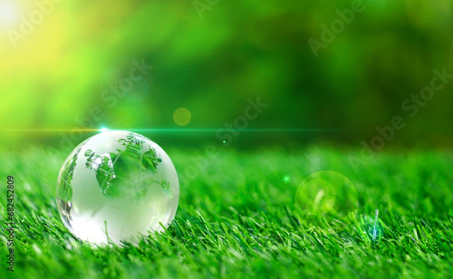 Glass earth globe crystal on green grass in the garden of safe world, save the planet concept, ecological, recycle, nature, environment friendly and World Environment Day.