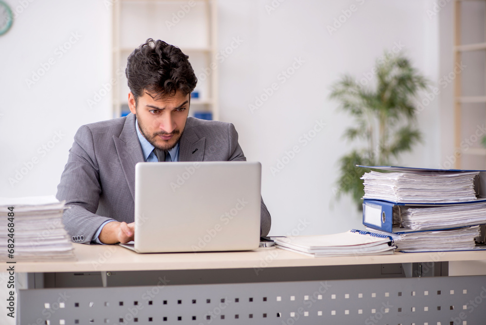 Young male employee and too much work in the office Young male employee and too much work in the office
