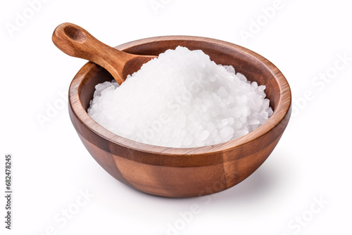 A wooden bowl filled with salt, viewed from above with a spoon next to it, laid flatly on a white surface.