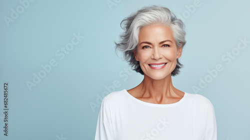 beautiful elderly woman model with beautiful gray hair posing in the studio on a pastel blue background. advertising beauty photo shoot. health and graceful aging. copy space. banner photo