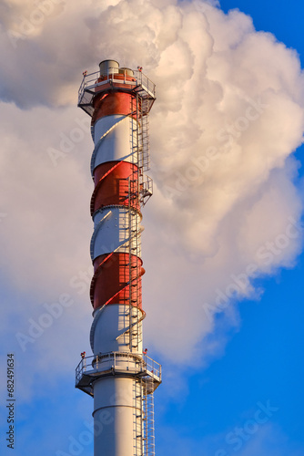 Tall power plant chimney with smoke