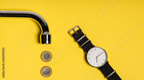 concept. metal tap spout on a yellow background, Polish zloty coins arranged in a row, and a watch with a white dial lying next to it. bright yellow image photo