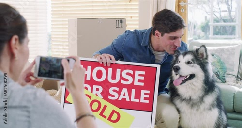 Man, dog and sold for sign by new home with photo by phone for memory, milestone or goal. Woman taking picture, husky and kiss with smile for bond, love and care for property, real estate or growth photo