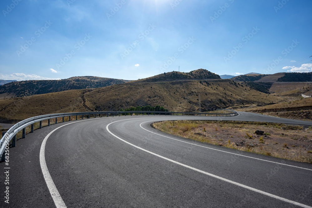 The desolate, empty and inviting highway stretching serpentine across the steppe. It is said that distance first accumulates inside a person, then it is only the road . Kars, Turkey.