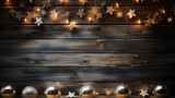 Christmas background with lights and baubles on dark wooden planks.